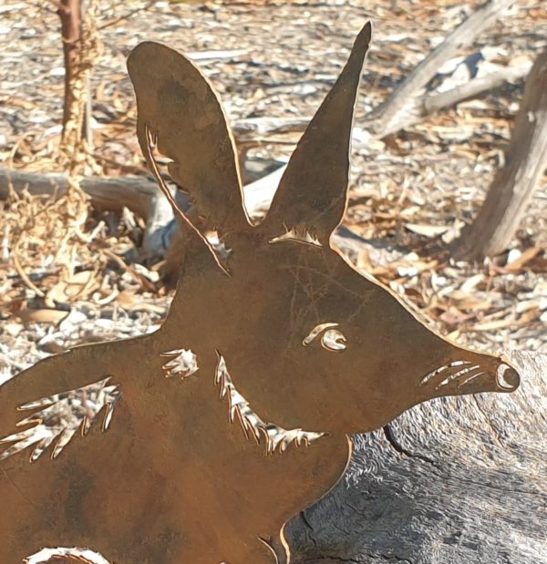 A handmade Bilby standing garden stake made from Corten steel, measuring 27 cm, showcasing its charming long-nosed design in an outdoor garden setting