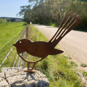 Wagtail Post Topper installed on a fence, with its rusted patina providing a rustic charm in a native Australian setting.