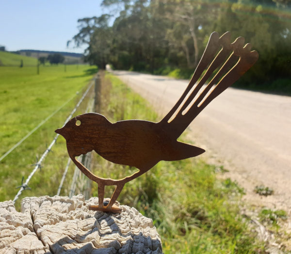 Wagtail Post Topper installed on a fence, with its rusted patina providing a rustic charm in a native Australian setting.