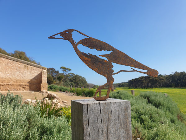 A rusted metal Magpie Post Topper crafted from Corten steel, set on a garden post, embodying the spirit of Australian wildlife and rustic charm.