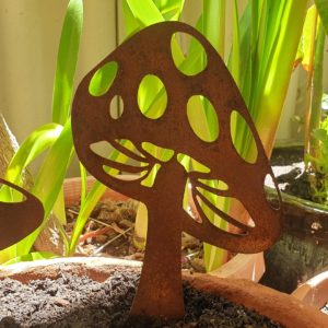 A rusted metal garden sculpture of a tall mushroom. Laser-cut from Corten steel, it stands 30 cm high and 18 cm wide, featuring a natural weathered patina. Perfect for garden beds or potted plants.