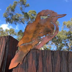 Kookaburra Post Topper perched on a wooden fence – A rusted metal Kookaburra Post Topper crafted from durable 1.6mm Corten steel, blending with the natural beauty of a wooden fence. Perfect for adding an Australian wildlife touch to your garden.