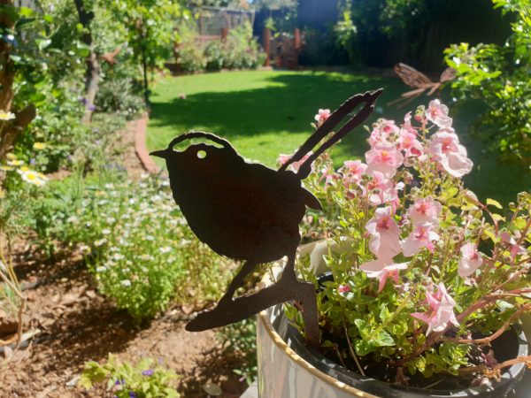 A side view of the Wren Australian Made Rusted Metal garden art, featuring a 22 cm height and rusted patina against a natural garden backdrop.